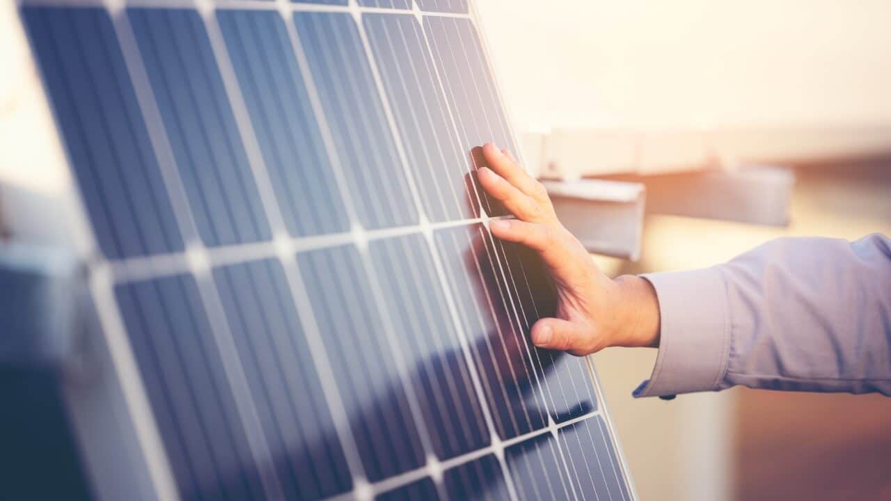 How solar panels are installed. A person's hand touching a solar panel.