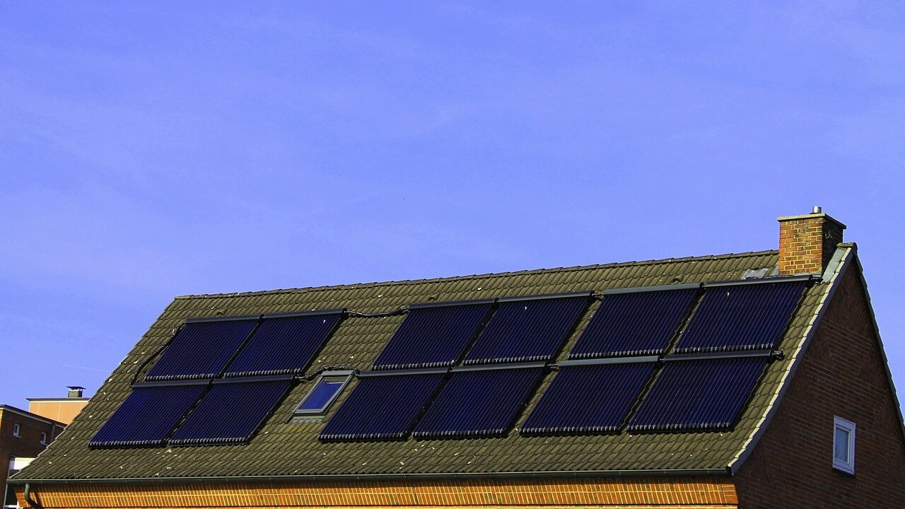 Solar panel grants. A set of solar panels installed on the roof of a house with blue sky above.